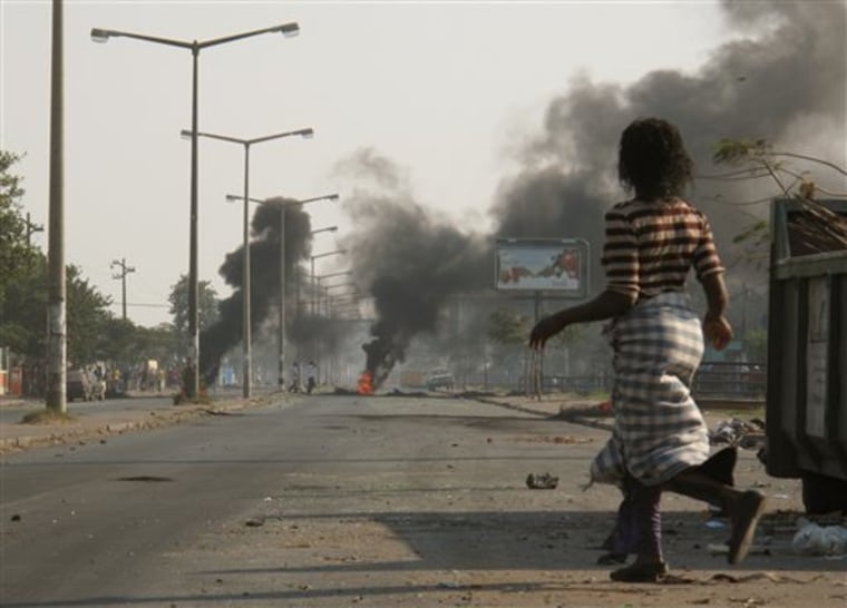 A woman passes near burning tires in a street in Maputo, Thursday Sept. 2, 2010 a day after police opened fire on stone-throwing crowds who were protesting rising prices in this impoverished country. 